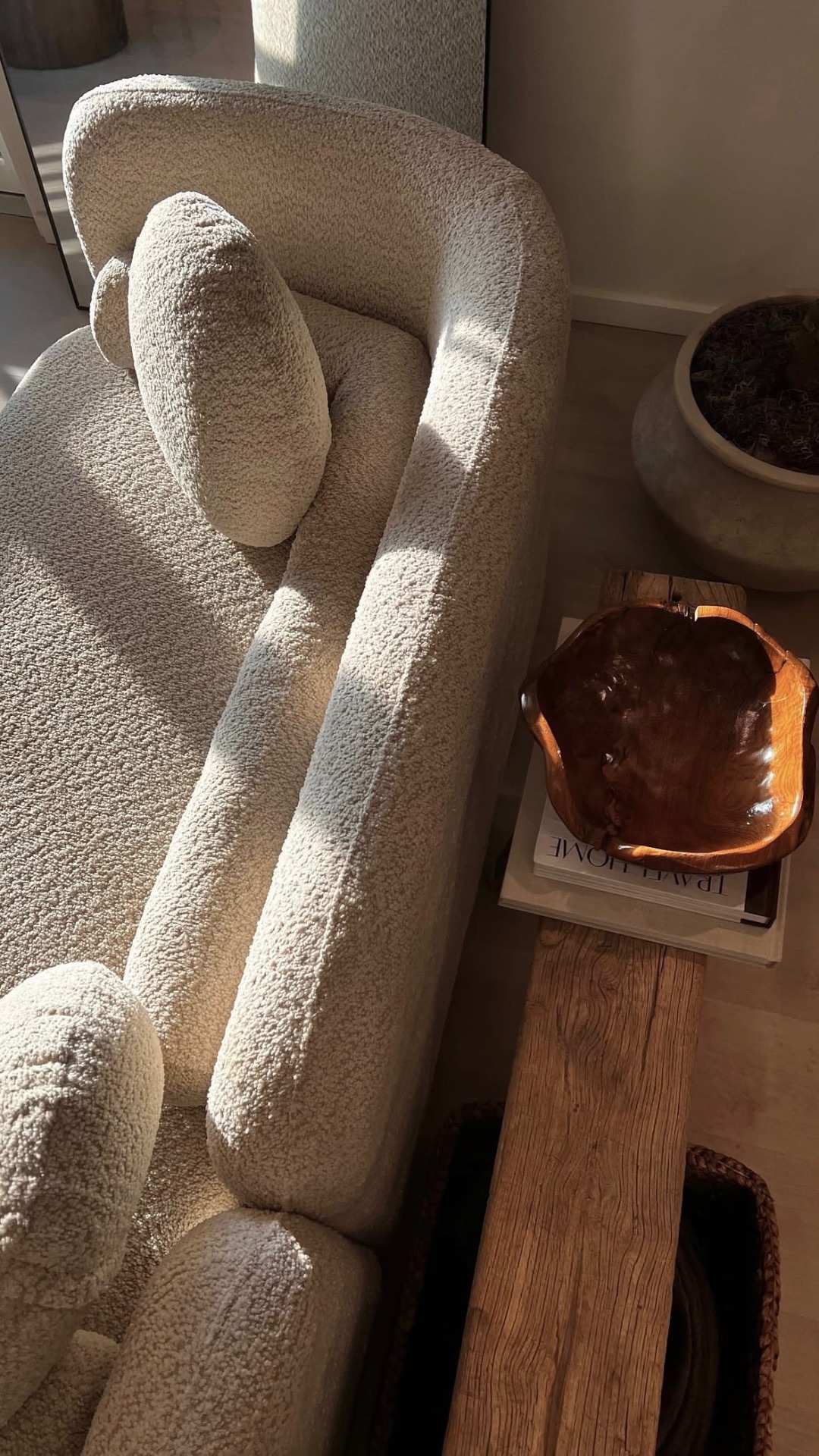 Bouclé sofa with sunlit wood bench and carved bowl at Carter Bridge Estate