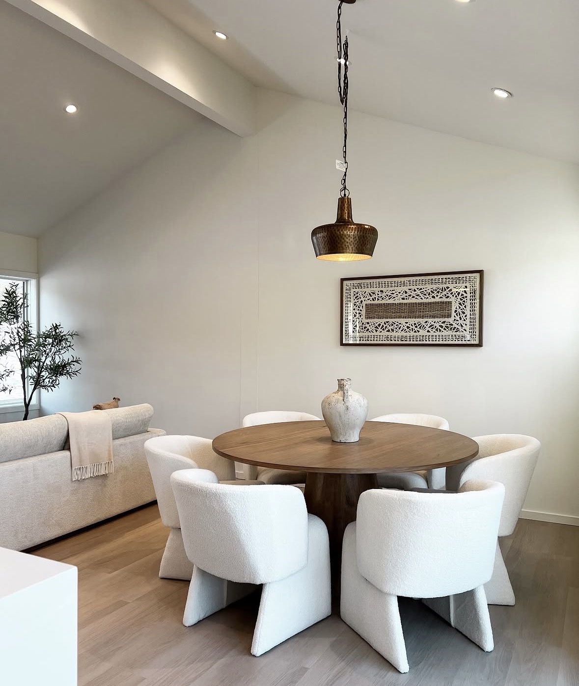 Vaulted dining room with bouclé chairs and a hammered pendant